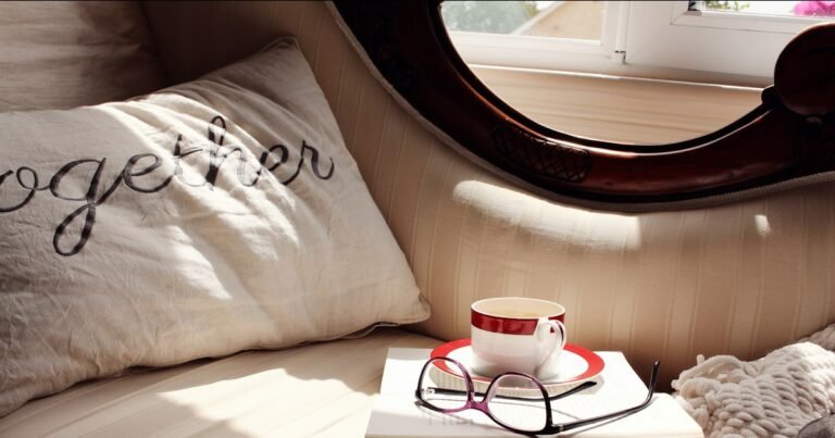 A coffee cup, open book, and eyeglasses arranged for a cozy reading session