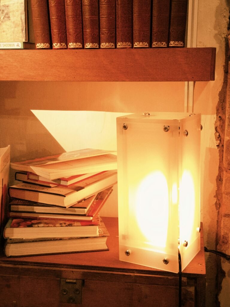 Warm reading lamp beside stacked books in a cozy reading nook
